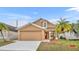 Two-story house with tan exterior, red door, and landscaped yard at 2267 Santa Lucia St, Kissimmee, FL 34743