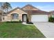 Tan one-story house with a white garage door and landscaped lawn at 3233 Egrets Landing Dr, Lake Mary, FL 32746