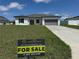 Well-maintained front yard with a 'For Sale' sign in front of a modern, single-story house at 105 Marion Oaks Manor, Ocala, FL 34473