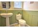 Charming half bathroom with pedestal sink and green wainscoting at 1102 Victoria Glen Dr, Sanford, FL 32773