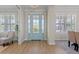 Light and airy entryway with light hardwood floors and a light blue door at 1406 Saxon Dr, New Smyrna Beach, FL 32169