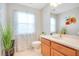 Bathroom with wood cabinets and a floral-patterned curtain at 1763 Stargazer Ter, Sanford, FL 32771