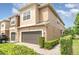 Tan two-story house with a brown garage door and manicured landscaping at 250 Merry Brook Cir, Sanford, FL 32771