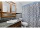 Bathroom featuring dark wood cabinetry with a granite countertop, toilet, and a shower/tub with patterned curtain at 2717 Rose Moss Ln, Orlando, FL 32807