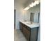 Elegant bathroom featuring a double sink vanity with modern faucets and a large mirror with decorative lighting at 27469 Black Kite Ave, Howey In The Hills, FL 34737