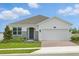 Inviting single-story home with a well-manicured lawn and a two-car garage showcasing a blend of modern architecture at 27469 Black Kite Ave, Howey In The Hills, FL 34737