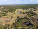 An overhead view of the property showing acreage, a pond, and tree line, emphasizing its privacy and natural beauty at 36129 E Eldorado Lake Dr, Eustis, FL 32736