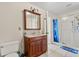 Well-lit bathroom with a vanity, toilet, and a shower behind a blue shower curtain at 36129 E Eldorado Lake Dr, Eustis, FL 32736