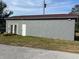 Exterior view of a grey building with two white doors, with hay bales stacked by the entrance at 36129 E Eldorado Lake Dr, Eustis, FL 32736