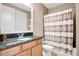 Bathroom with granite countertop, wood cabinets, and striped shower curtain at 10389 Henbury St, Orlando, FL 32832