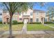 Tan two-story townhome with a white door, landscaping, and a walkway at 13651 Eridanus Dr, Orlando, FL 32828