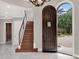 Elegant entryway with arched doorway, chandelier, and hardwood stairs at 9512 Tavistock Rd, Orlando, FL 32827