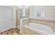 Bright bathroom with a soaking tub, glass shower, and tile accents with wood-look flooring at 10060 Pecan Hickory Way, Orlando, FL 32832
