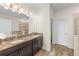 Bathroom featuring double vanity, granite countertop, dark cabinets and large mirror with decorative lighting at 10060 Pecan Hickory Way, Orlando, FL 32832