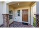 Front entry with a brown door, stone columns, and a brick walkway at 1490 Woodmont Blvd, Kissimmee, FL 34746
