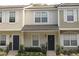 Tan townhome with dark gray door, shutters, and landscaping at 4145 Plantation Cove Dr, Orlando, FL 32810