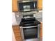 Close-up of the oven and microwave featuring stainless steel appliances and wooden cabinets at 63 York Ct, Kissimmee, FL 34758