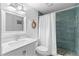 Bathroom with white vanity, teal tile shower, and pebble floor at 830 Garfish Ave, New Smyrna Beach, FL 32169