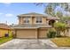 Two-story house with beige exterior, two-car garage, and lush landscaping at 8567 Baywood Vista Dr, Orlando, FL 32810
