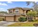 Two-story house with beige exterior, two-car garage, and mature shrubs at 8567 Baywood Vista Dr, Orlando, FL 32810