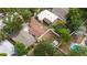An aerial shot of a home with a brown roof, white fence, and a backyard featuring a pool and lush greenery at 2002 Geigel Ave, Orlando, FL 32806