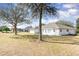 Spacious backyard with mature trees, a white home, and a screened-in porch in the distance at 36502 Barrington Dr, Eustis, FL 32736