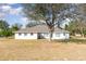 Backyard view of a white home with mature trees and manicured lawn at 36502 Barrington Dr, Eustis, FL 32736