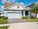 Light blue house with gray paver driveway, landscaping, and a two-car garage at 4567 Tribute Trl, Kissimmee, FL 34746