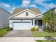 Two-story house with light blue exterior, gray paver driveway and landscaping at 4567 Tribute Trl, Kissimmee, FL 34746