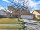 Single-story house with a brown roof, attached garage, and a large tree in the front yard at 626 Brookfield Loop, Lake Mary, FL 32746