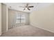 Neutral carpeted bedroom featuring a ceiling fan and a large window with white curtains at 8307 Fontera Dr, Davenport, FL 33896
