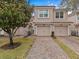 Tan two-story townhome with two-car garage and brick paver driveway at 8307 Fontera Dr, Davenport, FL 33896