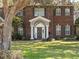 Up close view of a red brick two-story home with a well-manicured lawn and mature trees at 9501 Hempel Cove Blvd, Windermere, FL 34786