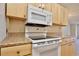 Close-up of kitchen with white appliances and wood cabinets at 12340 Tavares Ridge Ln # 111, Tavares, FL 32778