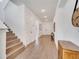 Inviting entryway with wood-look floors, white walls, staircase and a wooden cabinet with clock at 14789 Milfoil Ave, Orlando, FL 32827