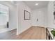 Hallway view to a bathroom and the front door with light walls and wood floors at 14789 Milfoil Ave, Orlando, FL 32827