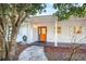 Front entry of a house with an orange door and white brick at 3645 Mirror Lake Dr, Apopka, FL 32703