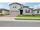 Charming two-story home featuring a gray exterior, brick driveway, and well-manicured landscaping at 3833 Giorgio Dr, Winter Haven, FL 33884