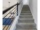 Stylish staircase featuring carpeted steps and an iron railing adjacent to an open kitchen design at 5003 Railroad Vine Aly, Winter Garden, FL 34787