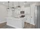 Modern kitchen with white cabinets, stainless appliances, island with stone countertop and pendant lighting at 5087 Railroad Vine Aly, Winter Garden, FL 34787