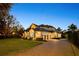 Exterior shot of the home at dusk with a brick driveway, manicured lawn, and illuminated landscaping at 6874 Valhalla Way, Windermere, FL 34786