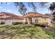 Tan house with a red door, lush landscaping, and a two-car garage at 7895 Saint Giles Pl, Orlando, FL 32835