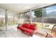 Bright sunroom with white tile floors, red sofa, and view of fenced backyard at 7909 Chartreux Ln, Maitland, FL 32751