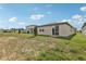 Home exterior with a sliding glass door and spacious backyard featuring a newly planted tree at 1373 Current Pl, Haines City, FL 33844