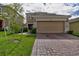 Two-story house with a beige exterior, brick accents, and a two-car garage at 1726 Tree Shade Dr, Davenport, FL 33837