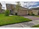 Two-story house with beige exterior, brick accents, and a two-car garage at 1726 Tree Shade Dr, Davenport, FL 33837