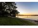 Scenic sunset view over calm lake, grassy yard, and small boat at 4108 Downeast Ln, Windermere, FL 34786