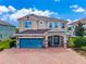 Beautiful two-story home with a teal garage door and brick paver driveway at 7723 Graben St, Kissimmee, FL 34747