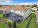 Aerial view of backyard with an enclosed pool area, green lawn, and nearby foliage at 8886 Fallen Oak Dr, Davenport, FL 33896