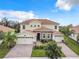 Stunning two-story home with a tile roof, lush landscaping, and a brick-paved driveway leading to a three-car garage at 8886 Fallen Oak Dr, Davenport, FL 33896